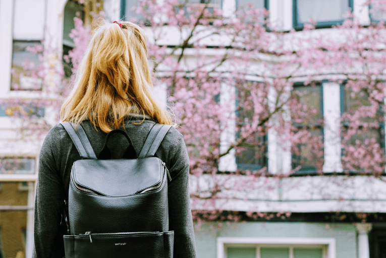 girl black backpack blossom tree street