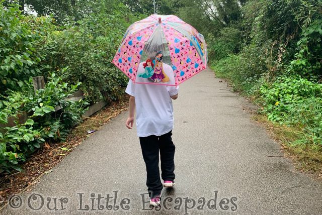 little e walking away holding umbrella