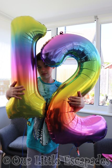 ethan holding number twelve rainbow balloons