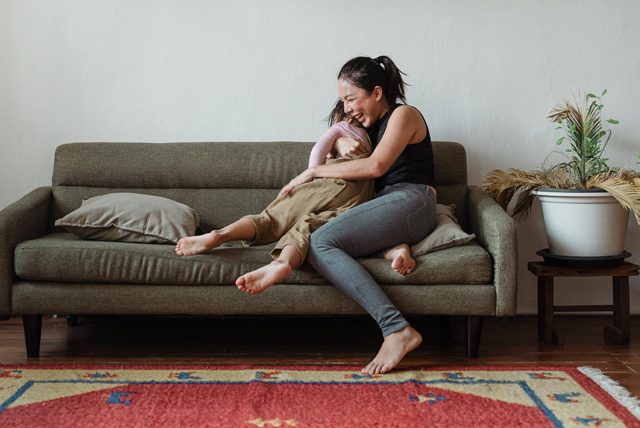 woman sitting on couch while hugging her child